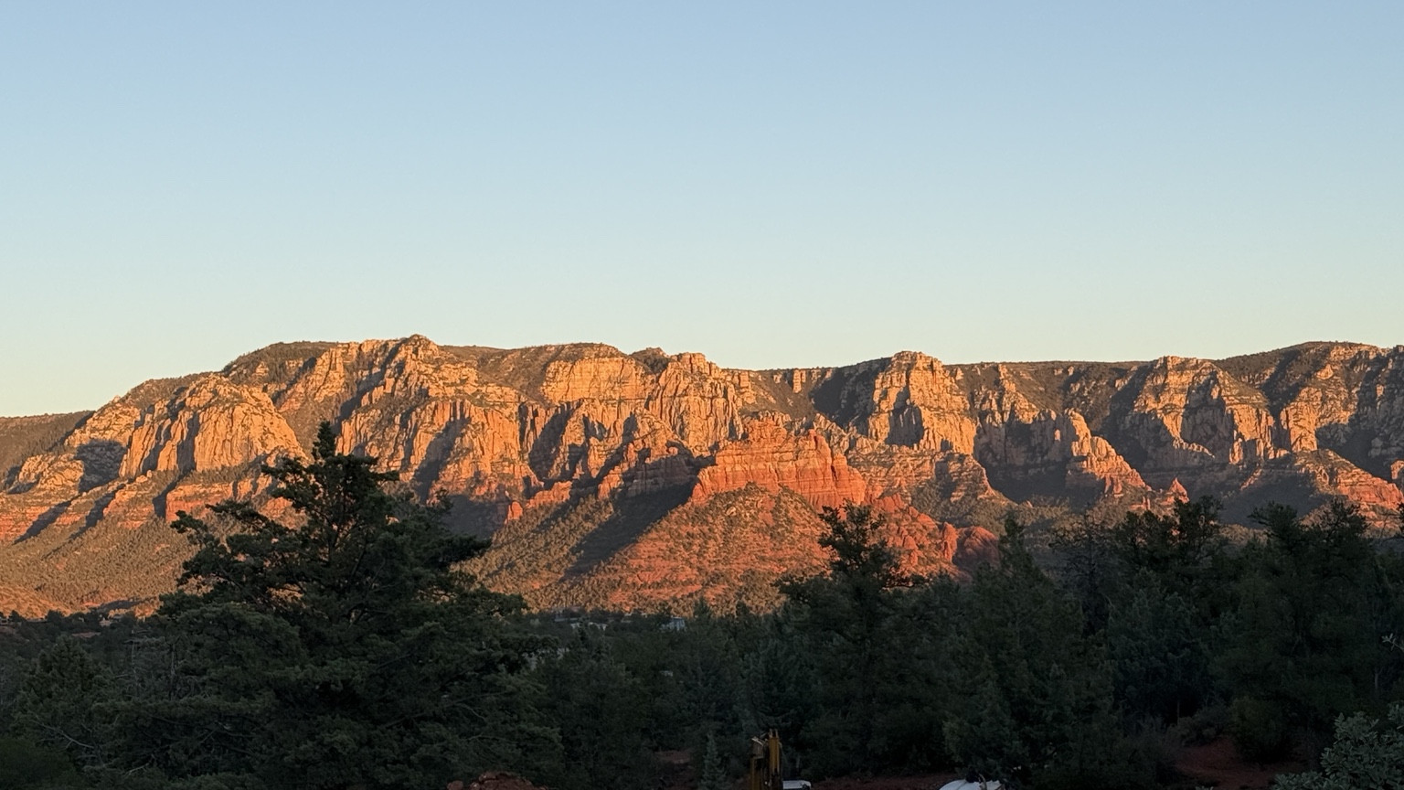 Sedona red-rock landscape above a wooded residential area at sunset